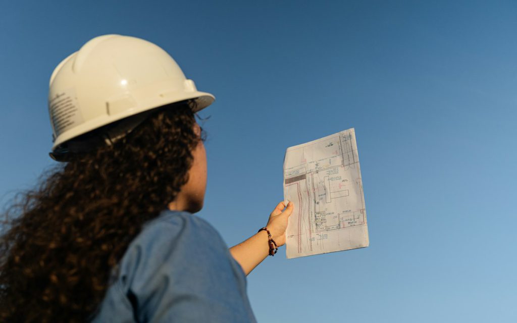 Engineer in a hard hat reviewing a printed drawing