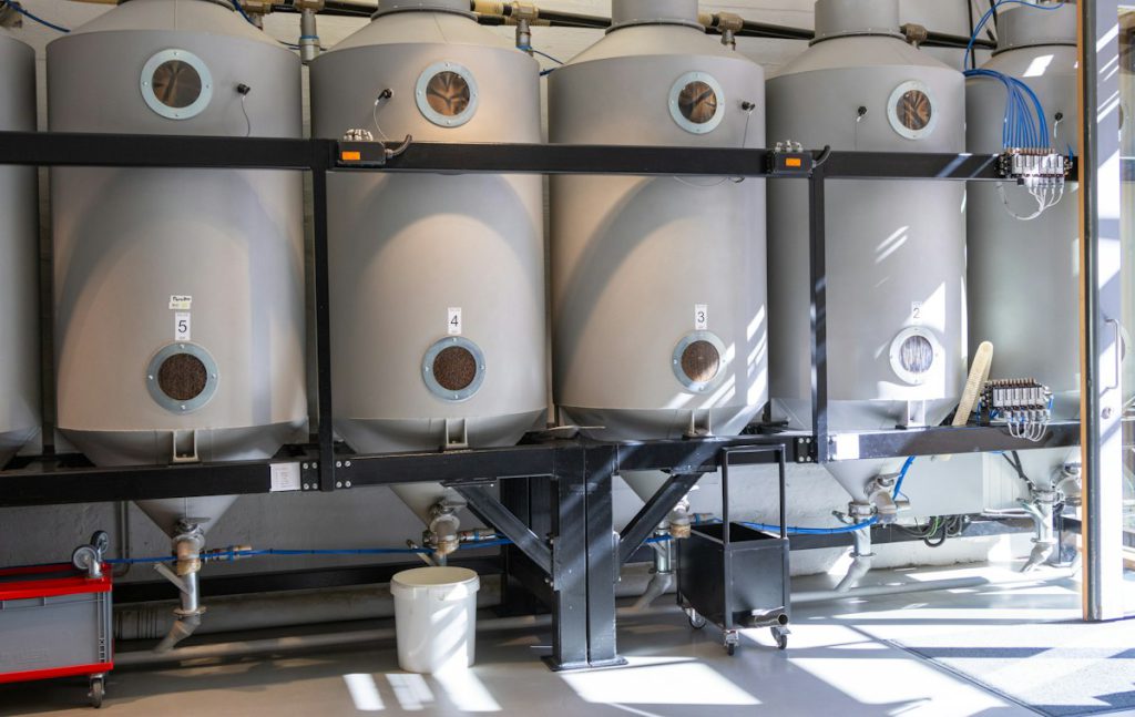 Row of stainless steel conical fermentation tanks in a production hall