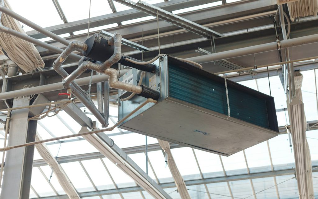 Ceiling-hung HVAC unit with refrigerant piping under a glass roof structure