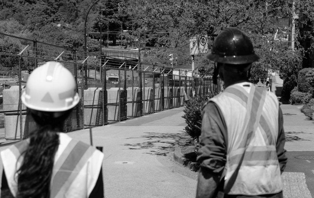 Two workers in hard hats and safety vests on a site walk