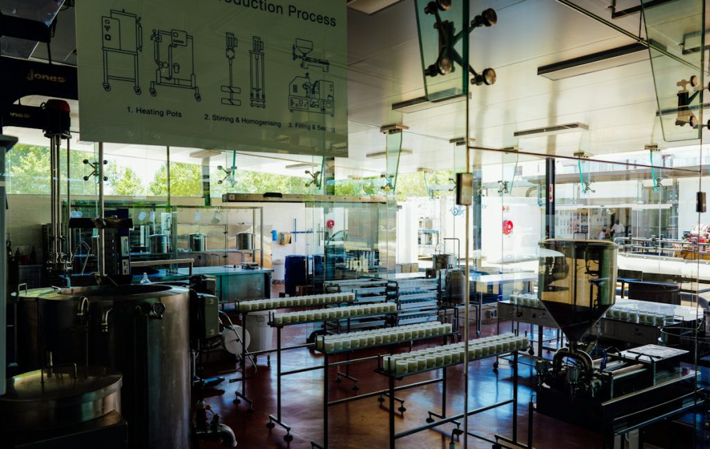 Food processing tanks and conveyors on a production floor behind a glass wall