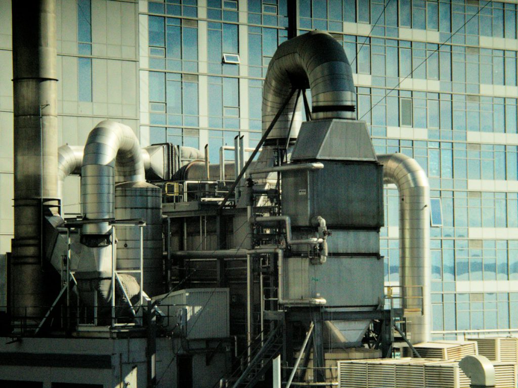 Rooftop air handling equipment and large ductwork beside a glass office building